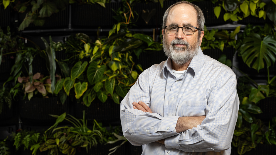 Ron Mittler posing in front of a plant wall.