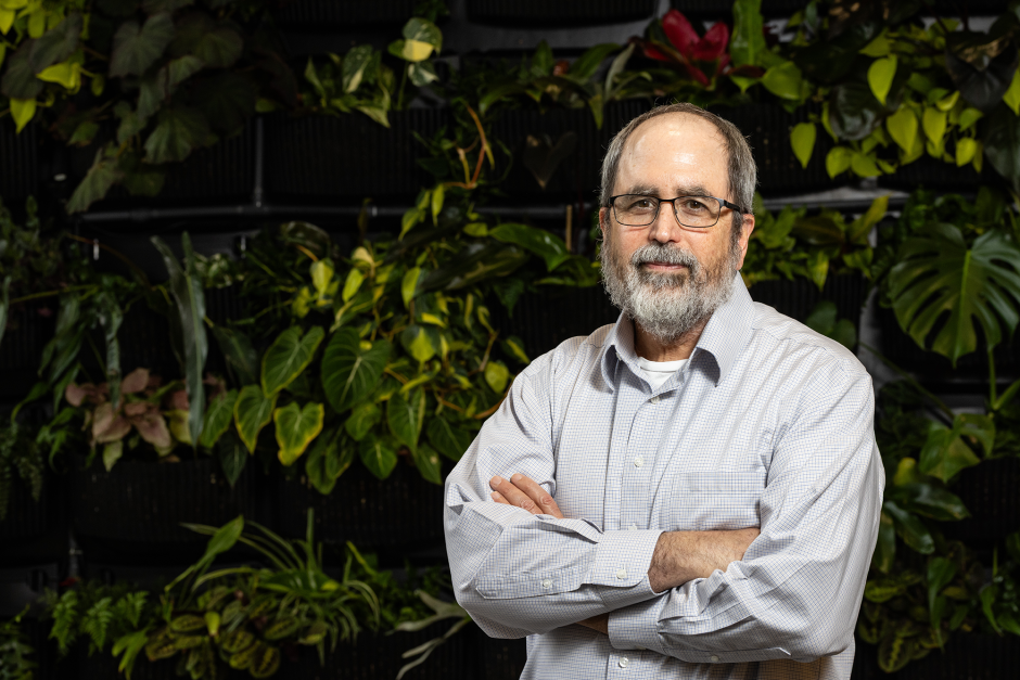 Ron Mittler posing in front of a plant wall.