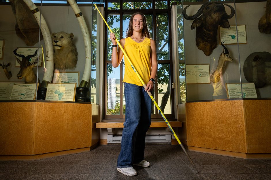 Student athlete holding a javelin in an archaeology museum