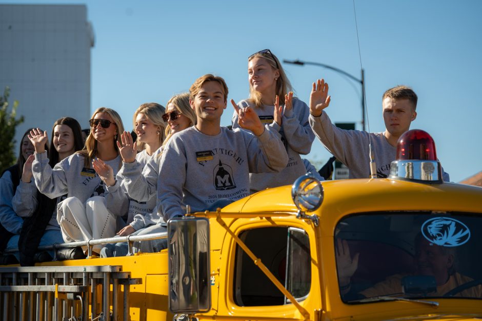 Group of Mizzou students waving from back of yellow fire truck