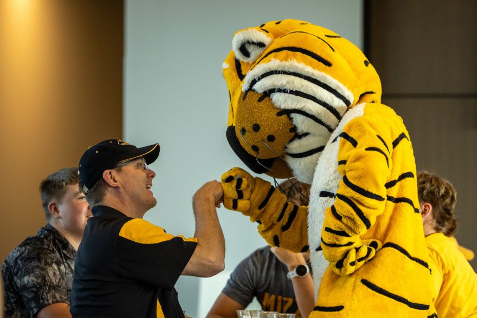 Man fist-bumping Truman the Tiger