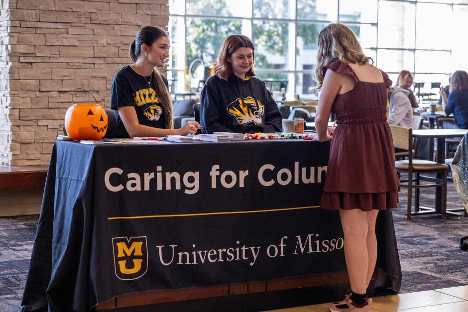 Two student workers talking to a student at a table