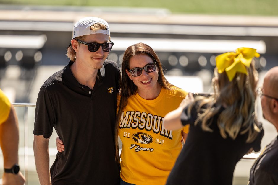 Two people posing for photo with football field in the background