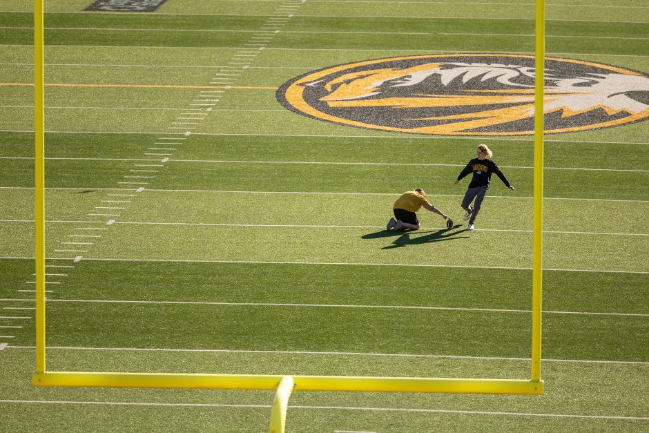 Person holding football on ground while another person kicks a field goal